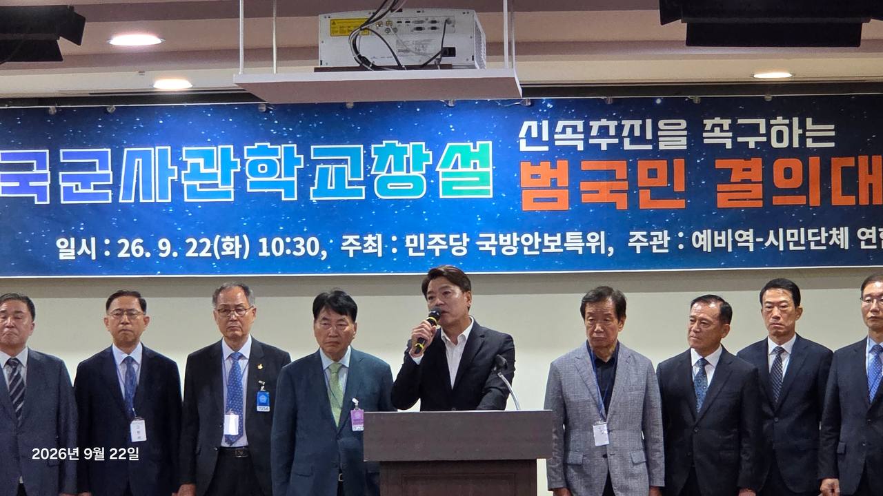 행사 현수막 앞 단상에서 마이크를 들고 발언하는 참석자